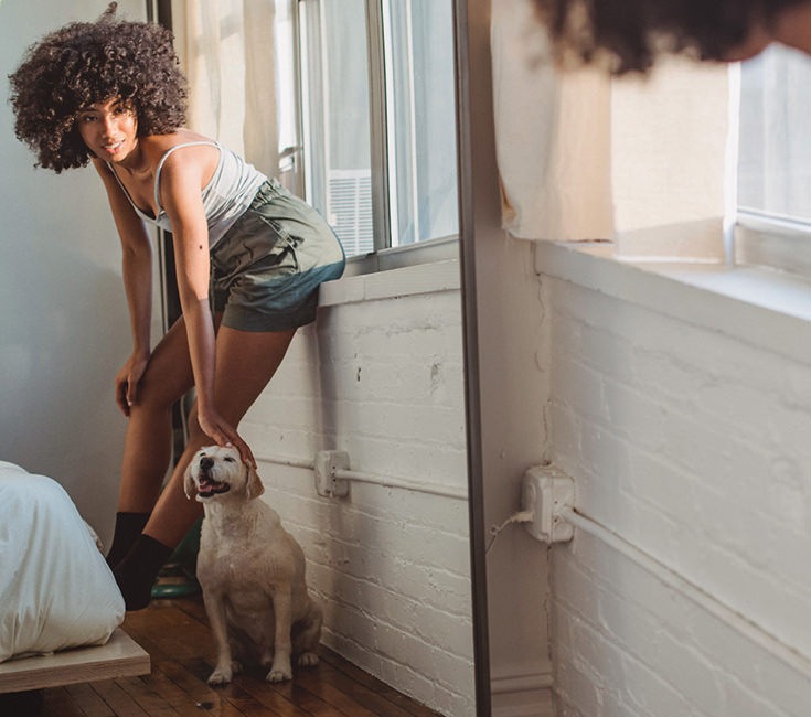 Woman and her dog standing in her bedroom 